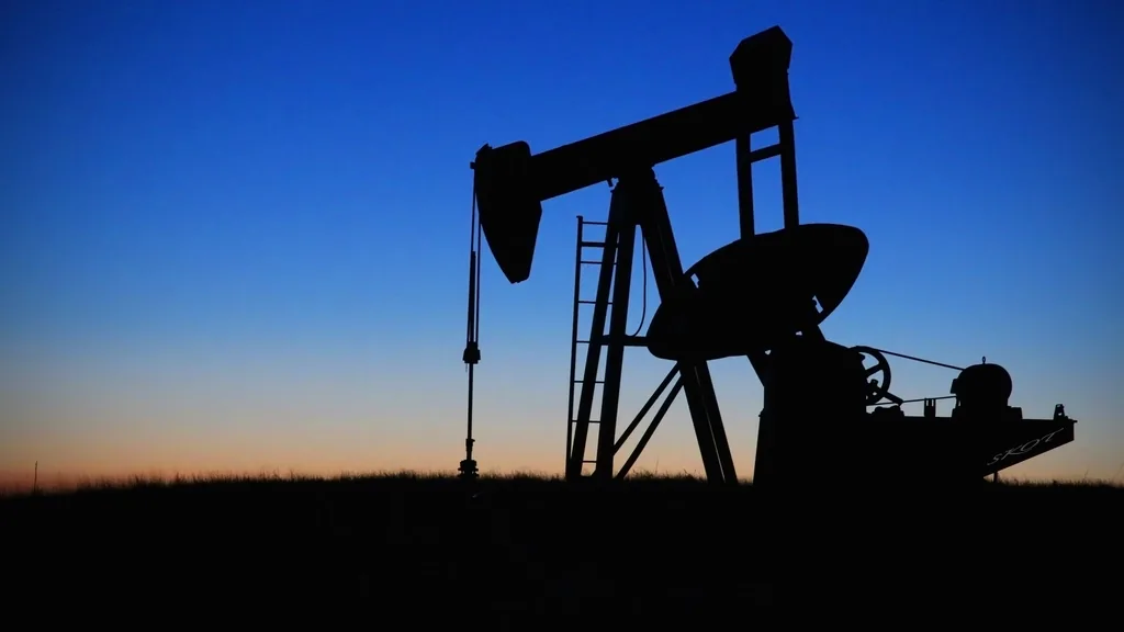 A pump jack silhouetted against the sky at dusk
